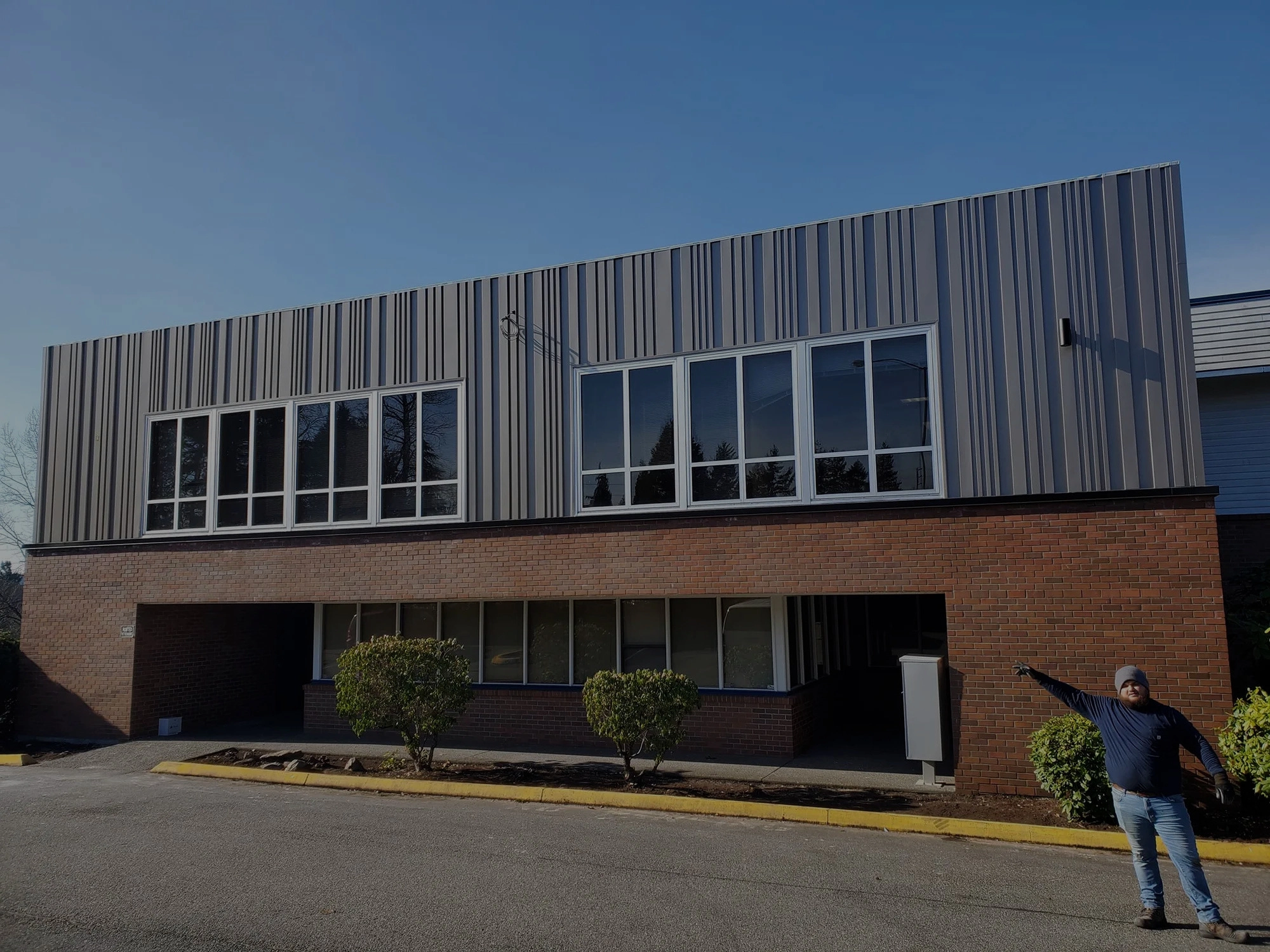 Large commercial building with vertical metal siding and brick base